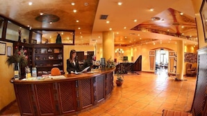A hotel lobby with a reception desk, seating area, and a staircase leading to upper floors. - Hotel Comillas (Comillas)