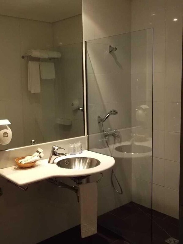A modern bathroom with a glass-enclosed shower, a white sink, and a mirror. - Hotel Comillas (Comillas)