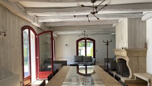 A spacious room with a long wooden table, a sofa, and a fireplace. - Design villa with swimming pool and tennis court in a hectare of fully enclosed grounds (Le Pont-de-Beauvoisin)