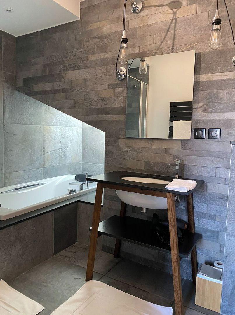 A modern bathroom with a freestanding sink, a large mirror, and a built-in bathtub.