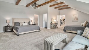 A spacious bedroom with two large beds, a bench, and a desk area. - Sunset Retreat Sleeps 30 | Hot Tub | Ping Pong | (Stevensville)