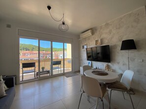 A modern living room with a balcony, a flat-screen TV, and a dining area.