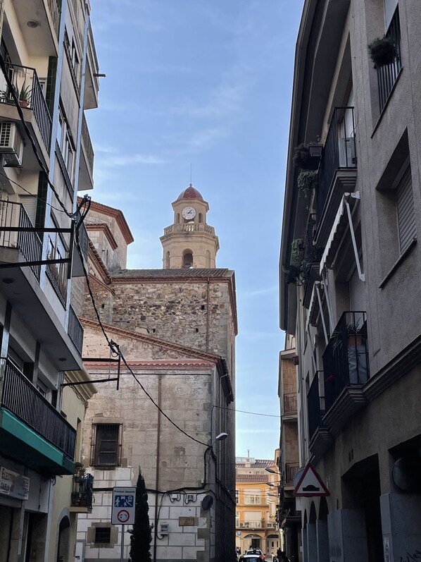 Una stretta via con edifici storici, una torre dell'orologio e un cartello che indica una zona pedonale.