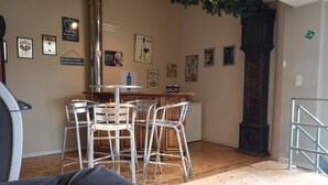 A cozy room with a wooden floor, a dining area with metal chairs, a bar area, and a staircase. - Mooi gerenoveerde boerderij van 1872. (Büllingen)