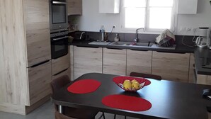 Eine moderne Küche mit Holzausstattung, einem Backofen, einer Spüle und einem Essbereich mit Tisch und Stühlen.