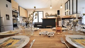 Une table à manger dressée avec des assiettes, des verres et une bouteille de vin, entourée d’armoires et d’appareils électroménagers de cuisine.