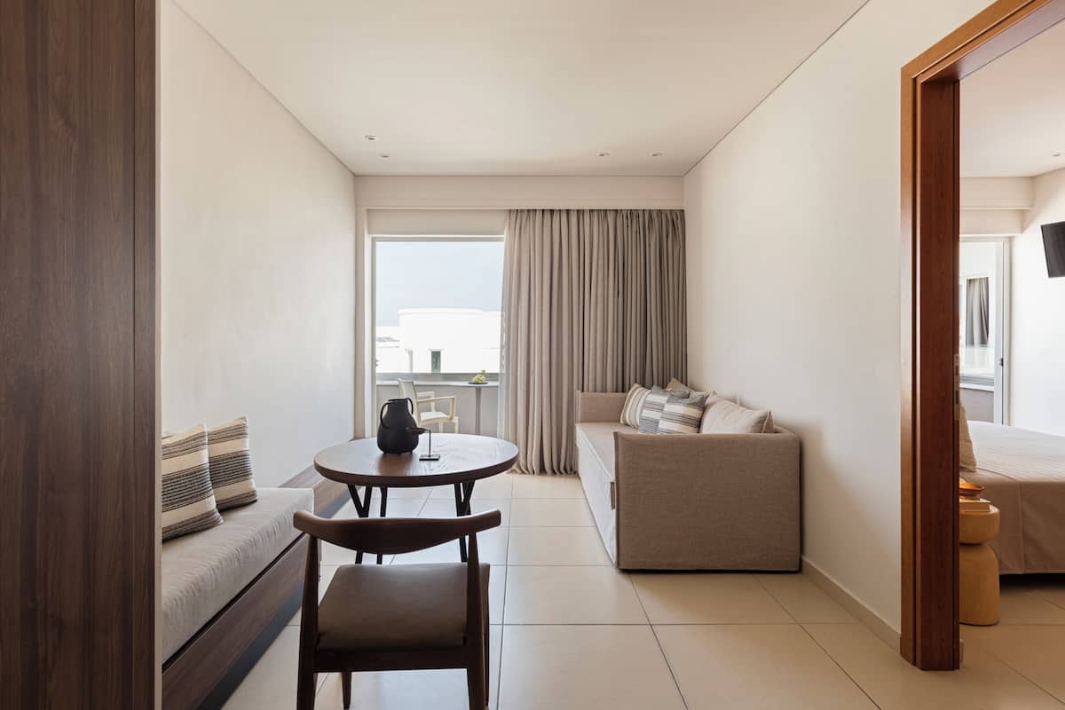 A modern hotel room with a sofa, a small table, a chair, and a bed.