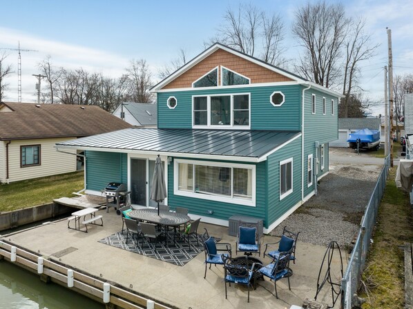 Ein zweistöckiges Haus mit überdachter Terrasse, komplett mit Tisch und Stühlen.