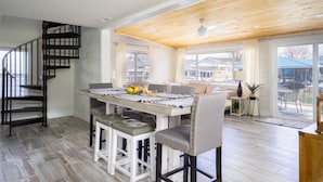 Una cocina moderna con una isla central, una escalera en espiral y ventanas grandes que ofrecen vistas al exterior.