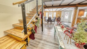 Eine Holztreppe mit Metallgeländern, ein Essbereich mit einem runden Tisch und weihnachtliche Dekorationen.