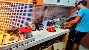 Una cocina con estufa a gas, cafetera y diversos utensilios de cocina.