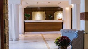 Un área de recepción con un mostrador de mármol, columnas blancas y una silla azul.