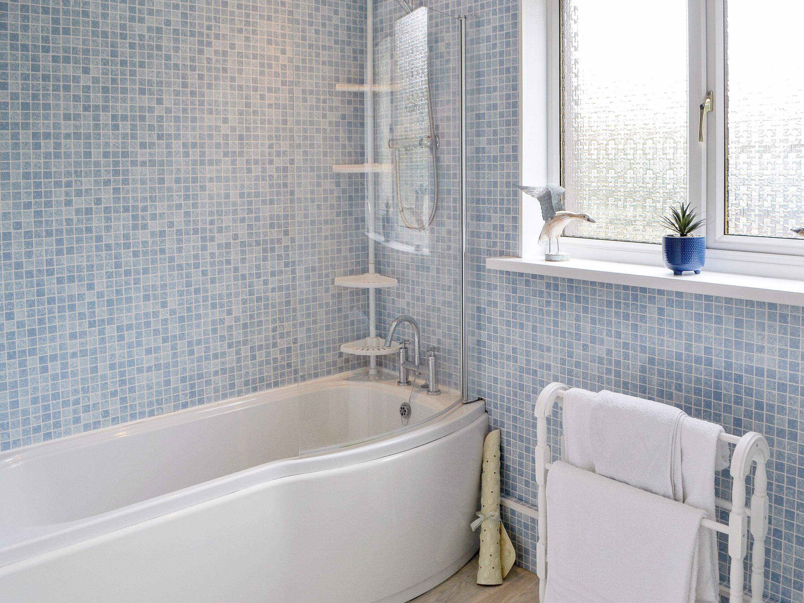 Un baño con bañera, ducha con mampara de cristal y ventana con vistas.