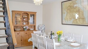 Una sala da pranzo con un armadietto in legno, un lampadario e una mappa appesa al muro.