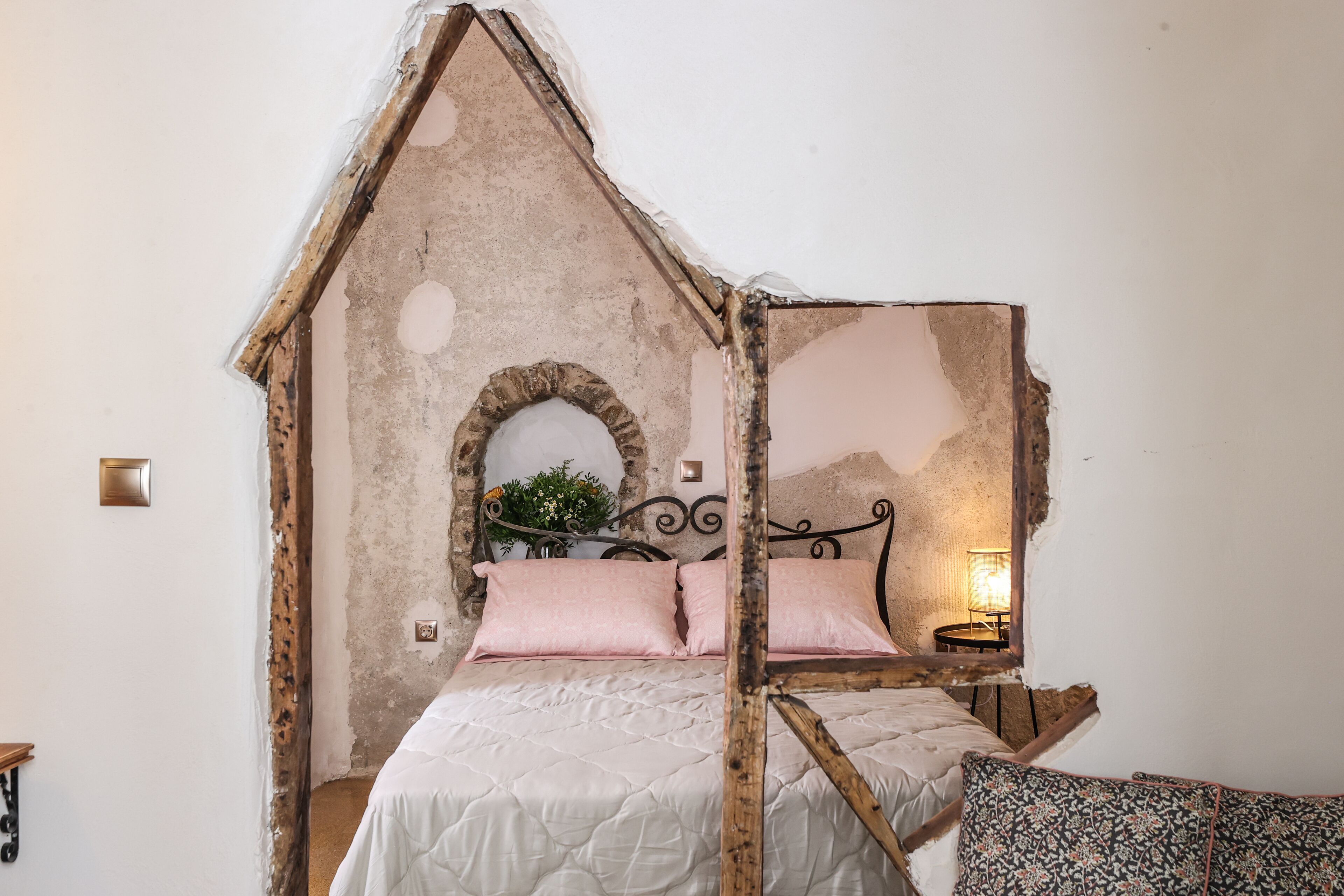 Ein Schlafzimmer im rustikalen Stil, mit einem Bett und einem Holzkopfende sowie einem Steingewölbe.