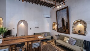 A cozy room with a wooden dining table, chairs, a sofa, and a large mirror. - Sikate Hospitality (Mykonos)