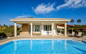 A poolside area with a covered patio, a pool, and outdoor furniture.