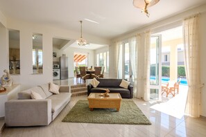 A spacious living area with a sofa, coffee table, and dining set.
