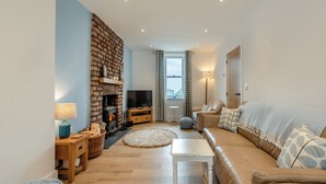 A living room with a fireplace, sofa, TV, and a view of the outdoors. - 3 bedroom accommodation in Square and Compass, near Haverfordwest (Square and Compass, near Haverfordwest)