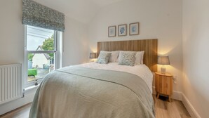A bedroom with a bed, bedside lamps, a window, and a radiator. - 3 bedroom accommodation in Square and Compass, near Haverfordwest (Square and Compass, near Haverfordwest)