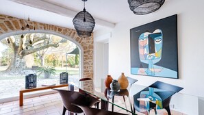 A modern interior with a stone archway, a dining area with chairs and a table, and a large abstract painting on the wall. - 18th century Provencal country house (Sarrians)