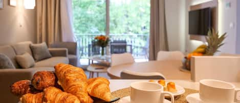 Un comedor con cruasanes, tazas de café y una piña sobre la mesa.