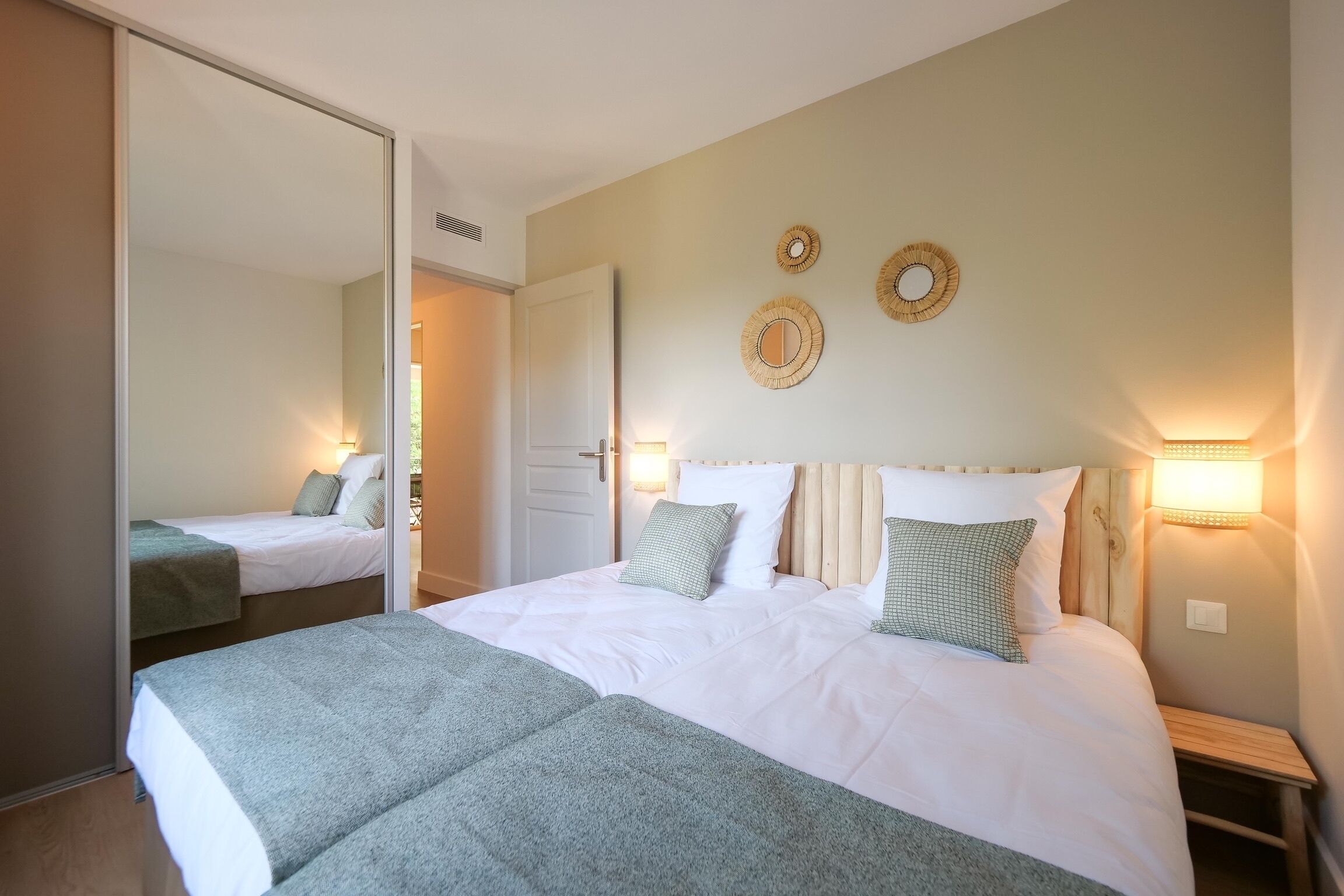 Et hotelværelse med en stor seng, et spejl og to væglamper.