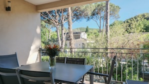 Ein Balkon mit Tisch und Stühlen mit Blick auf einen Garten und ein Gebäude.