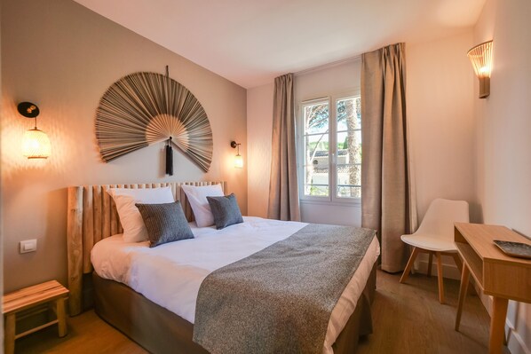 A bedroom with a bed, bedside table, chair, and a wall-mounted fan.