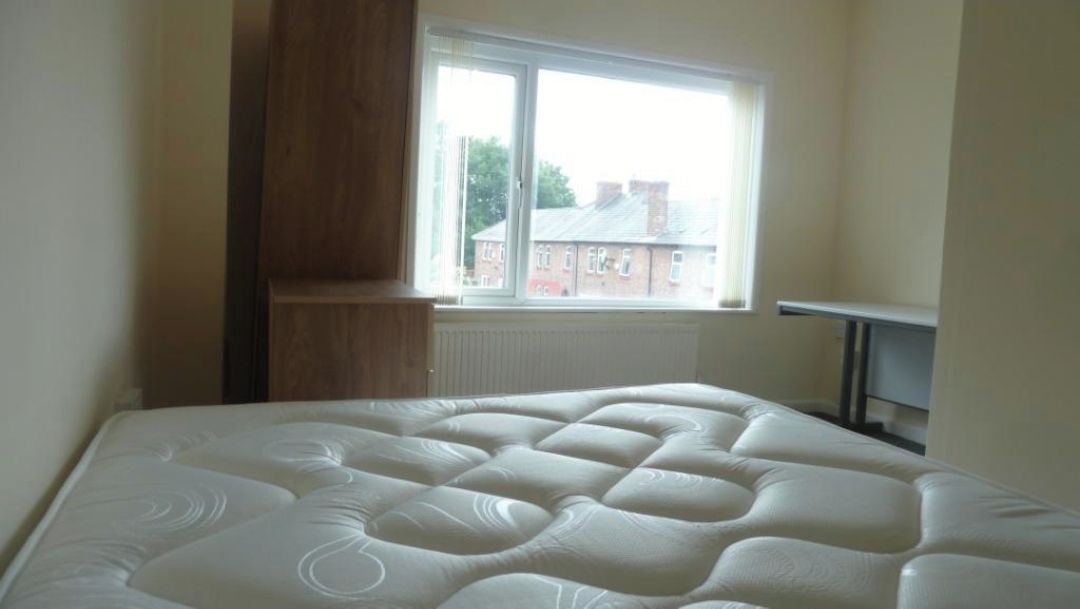 A bedroom with a bed, a window, and a radiator.