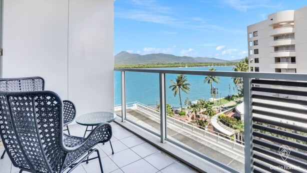 A balcony with a view of a lake, palm trees, and mountains. - Studio Stay near Marina with Pool, Gym and Sauna (Cairns City)