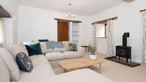 Una sala de estar acogedora con un sofá, una mesa de centro, una chimenea y una planta.