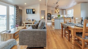 A spacious living area with a sofa, wooden dining table, and a kitchen in the background. - 2 bedroom accommodation in Willington, near Derby (Willington, near Derby)
