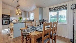 A modern kitchen with a central island, wooden dining table, and chairs. - 2 bedroom accommodation in Willington, near Derby (Willington, near Derby)