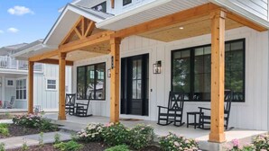 A two-story house with a covered porch, large windows, and a well-maintained garden. - ExpERIEnce South Haven | Beach Farmhouse Steps to South Beach and Lake Michigan (South Haven)