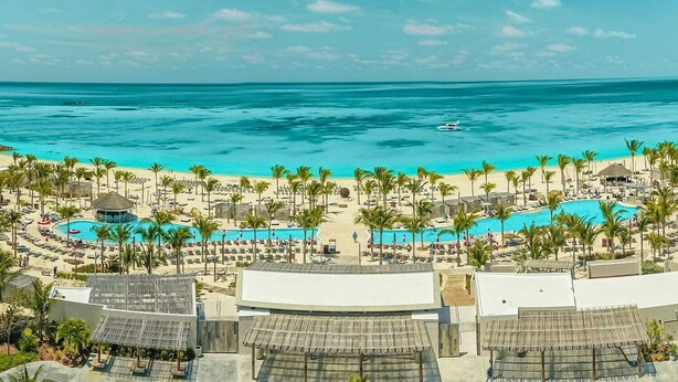 Ein Resort mit mehreren Schwimmbecken, Palmen und einem Strand.