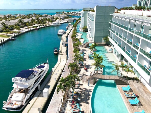 A marina with yachts docked, a swimming pool, and a resort building.