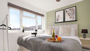A bedroom with a bed, a window with a view, a tray with breakfast, and two framed pictures on the wall. - Stylish House • Sleeps 6 • Driveway Parking • Garden • Fast Wifi • Self-Check-In • Yoko Property (Coventry)