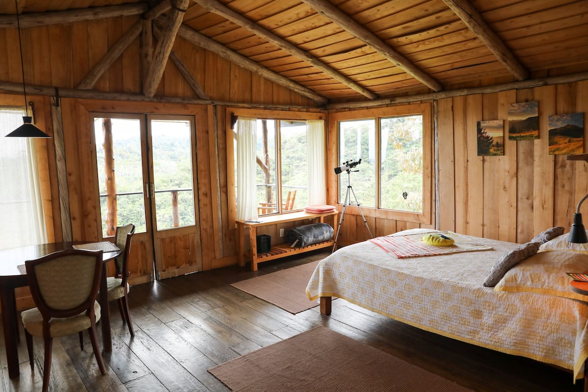 A wooden cabin with a bed, a desk, and a chair.