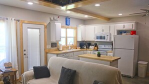 Une cuisine de taille réduite avec des meubles blancs, un four à micro-ondes, un réfrigérateur et un plan de travail en bois.