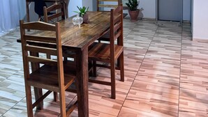 Ein Essbereich mit Holztisch und Stühlen, einem Bild an der Wand und einem Blumentopf.
