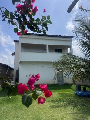 A two-story building with a flat roof and a balcony on the upper floor.