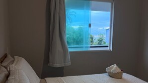 Ein Schlafzimmer mit Bett, einem Fenster und Blick sowie einem Vorhang.