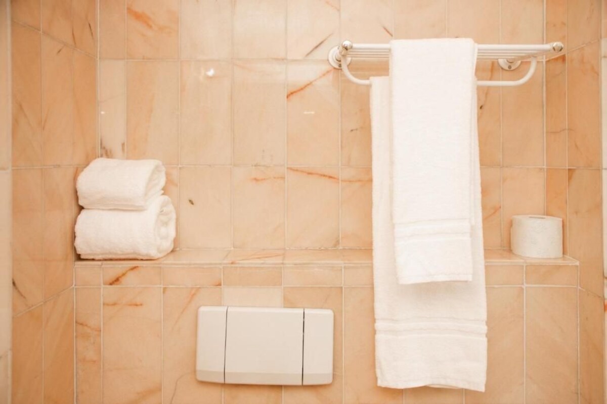 A bathroom with marble tiles, a towel rack, a towel, and a toilet paper holder.