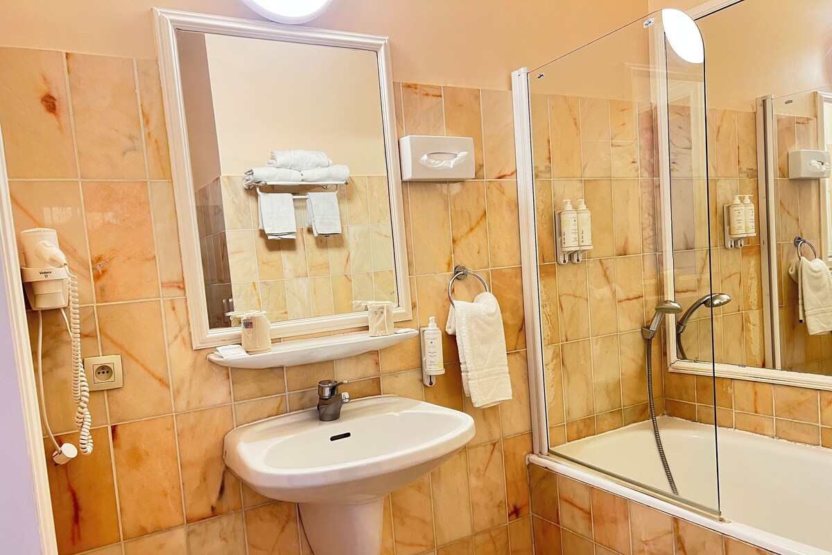 A bathroom with a sink, mirror, towel rack, and a glass-enclosed shower area.