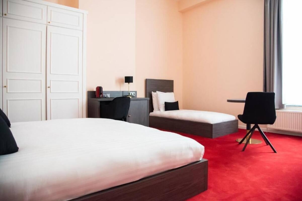 A hotel room with a large bed, a smaller bed, a desk, and a chair.