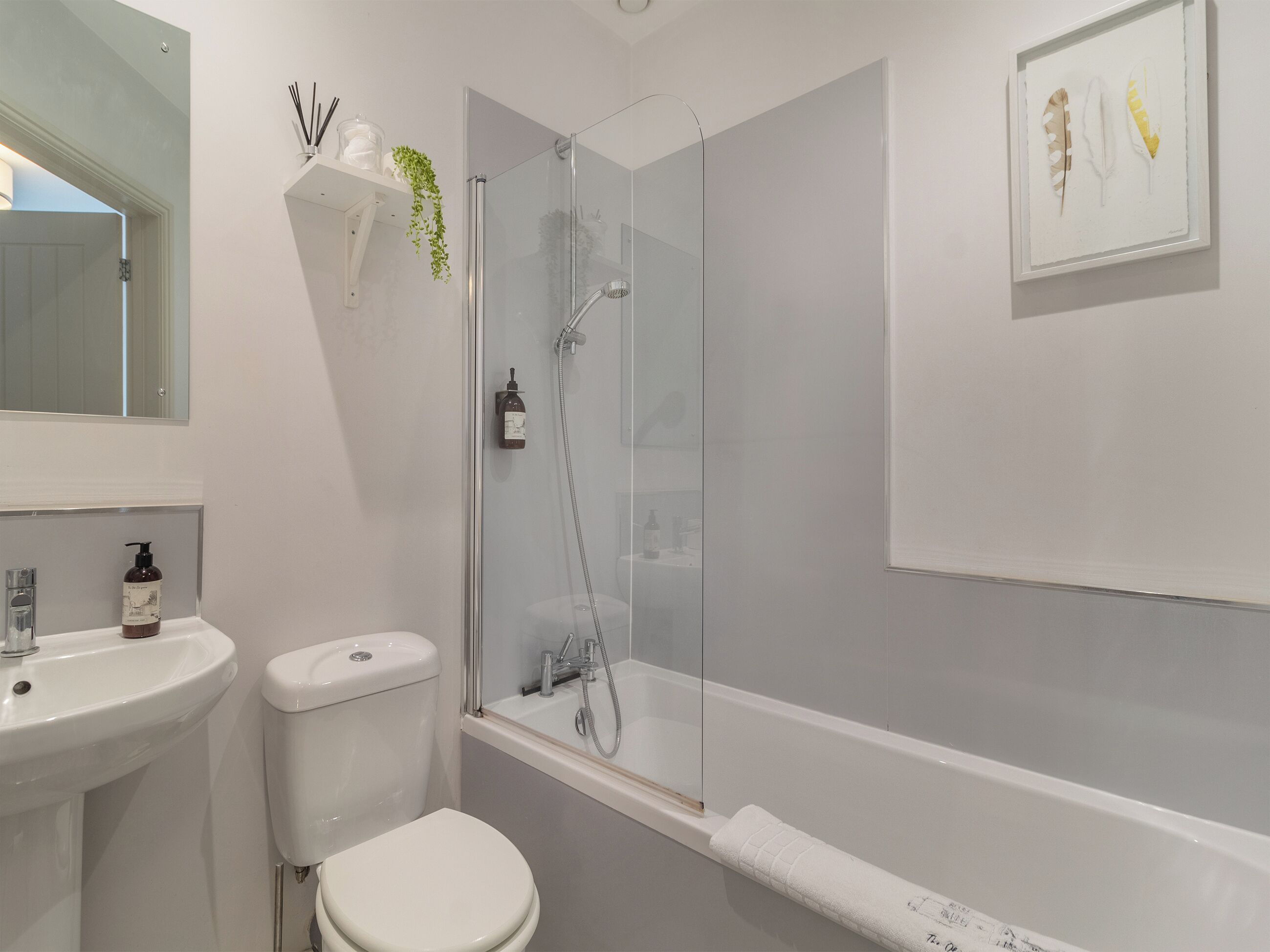A modern bathroom with a glass-enclosed shower, a white sink, and a toilet.