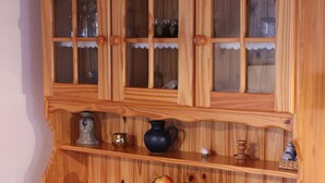 Een houten kast met meerdere lades en planken, vol met diverse spullen zoals een vaas, een fruitschaal en decoratieve objecten.