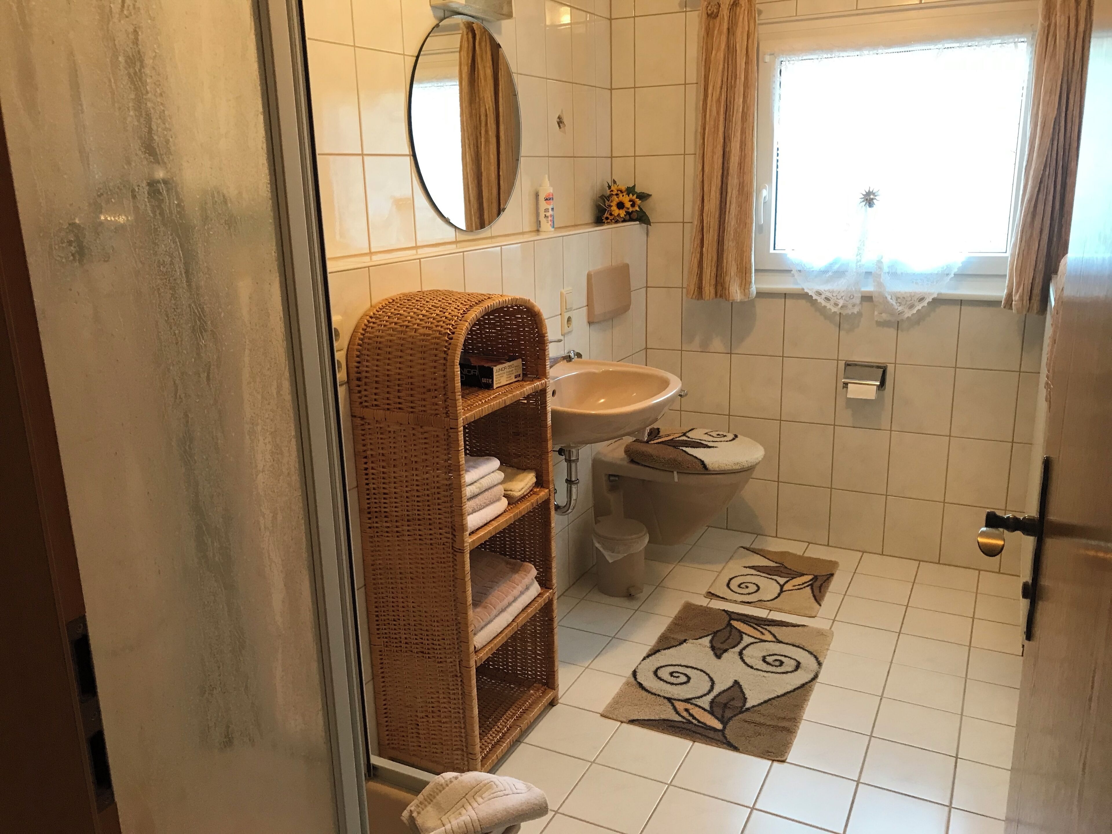 Une salle de bain équipée de toilettes, d’un lavabo, d’un panier en osier et de quelques tapis décoratifs.