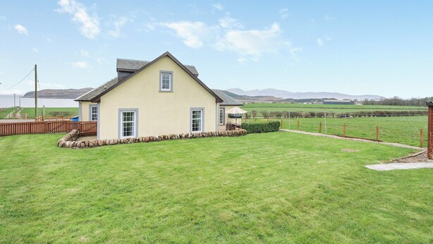 A single-story house with a gabled roof, a stone foundation, and a well-maintained lawn. - 4 bedroom accommodation in Kingarth (Kingarth)